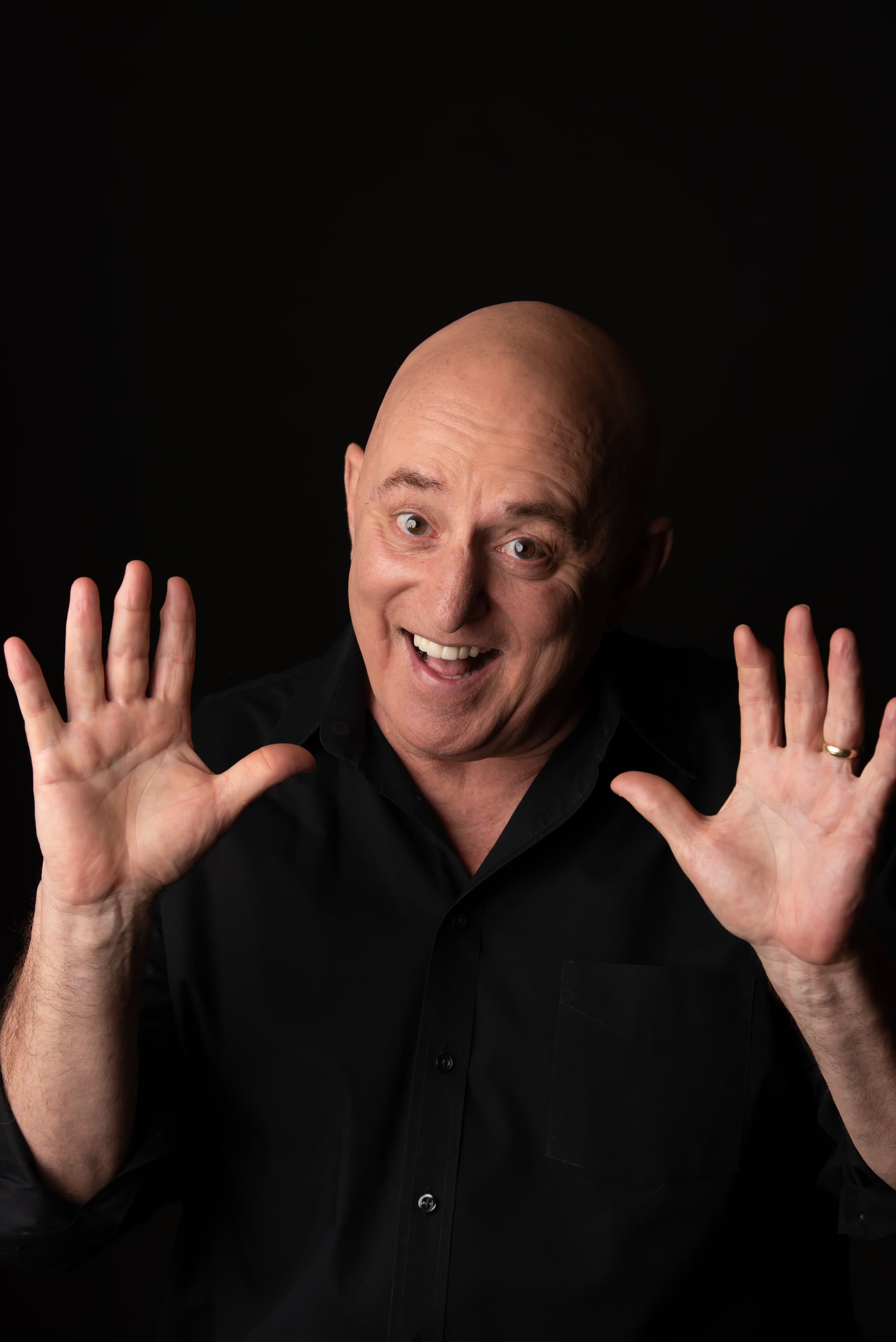Scott Record, both hands raised, caught mid-punchline